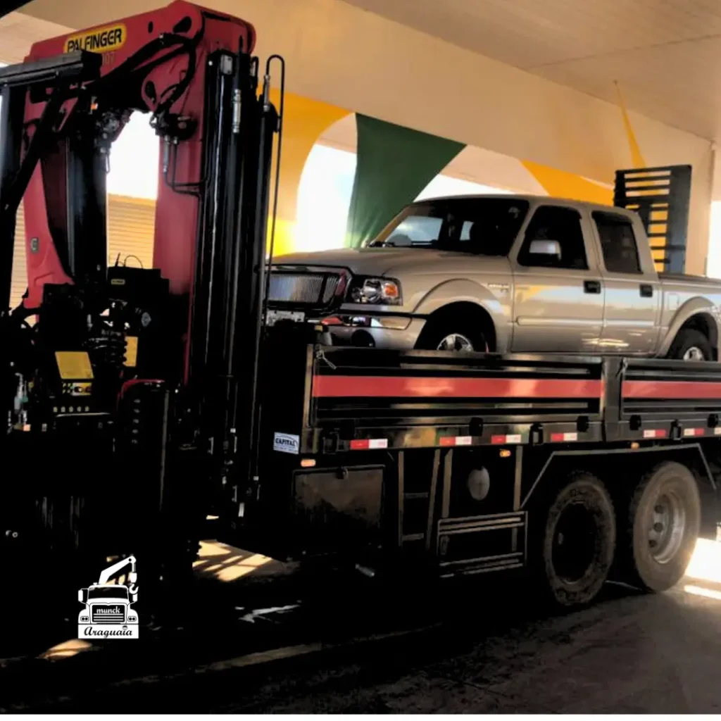 Caminhão-guincho com Munck transportando uma caminhonete em ambiente coberto, ideal para remoção e resgate veicular com equipamento hidráulico de alta capacidade. Serviço oferecido pela Munck Araguaia com segurança e eficiência.